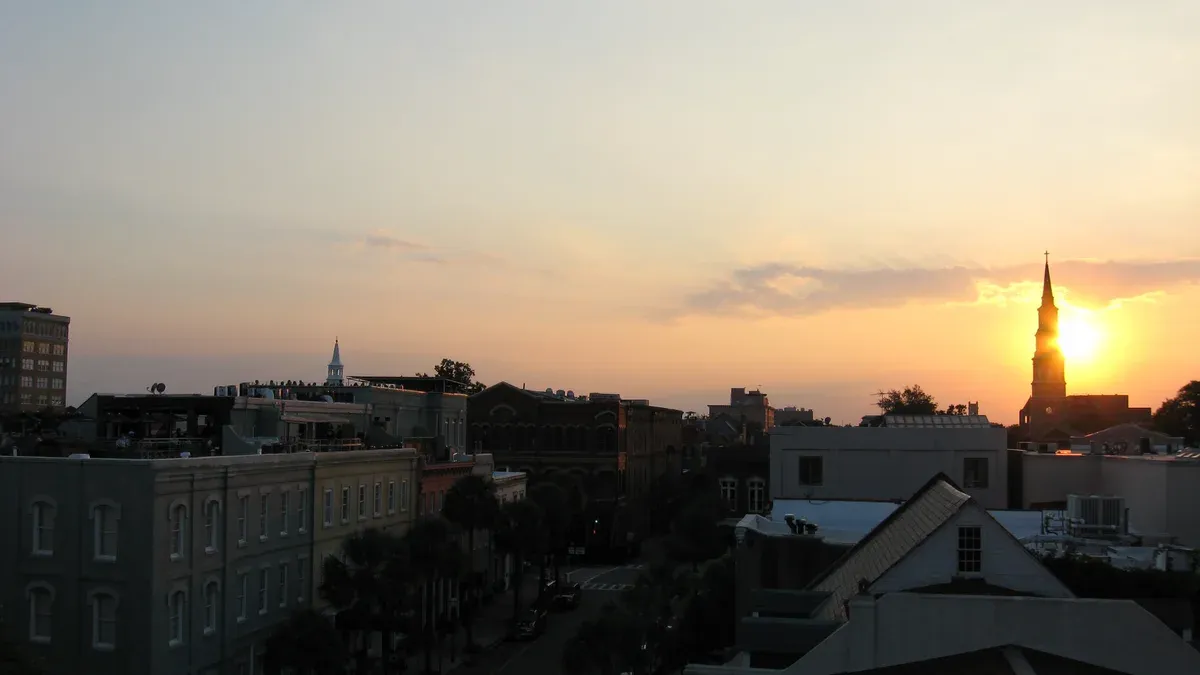 Sunset over Charleston rooftops near the harbor, the light a sunset party boat in Charleston sails into